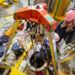 Confined space entry team using tripod and retrieval system for worker access.