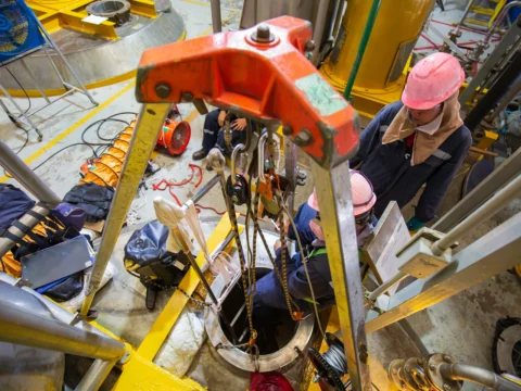 Confined space entry team using tripod and retrieval system for worker access.