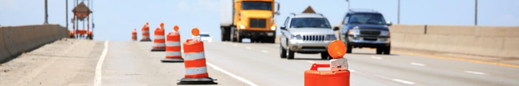 Work zone on a highway with actual vehicles and traffic control measures in effect as taught in this Spanish safety course.