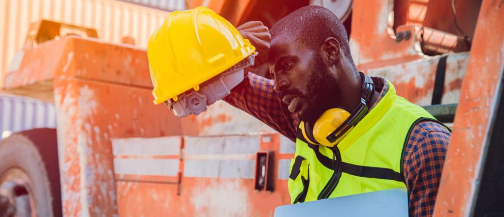 Tired stress worker sweat from hot weather in summer working in port goods cargo shipping logistic ground, Black African race people.