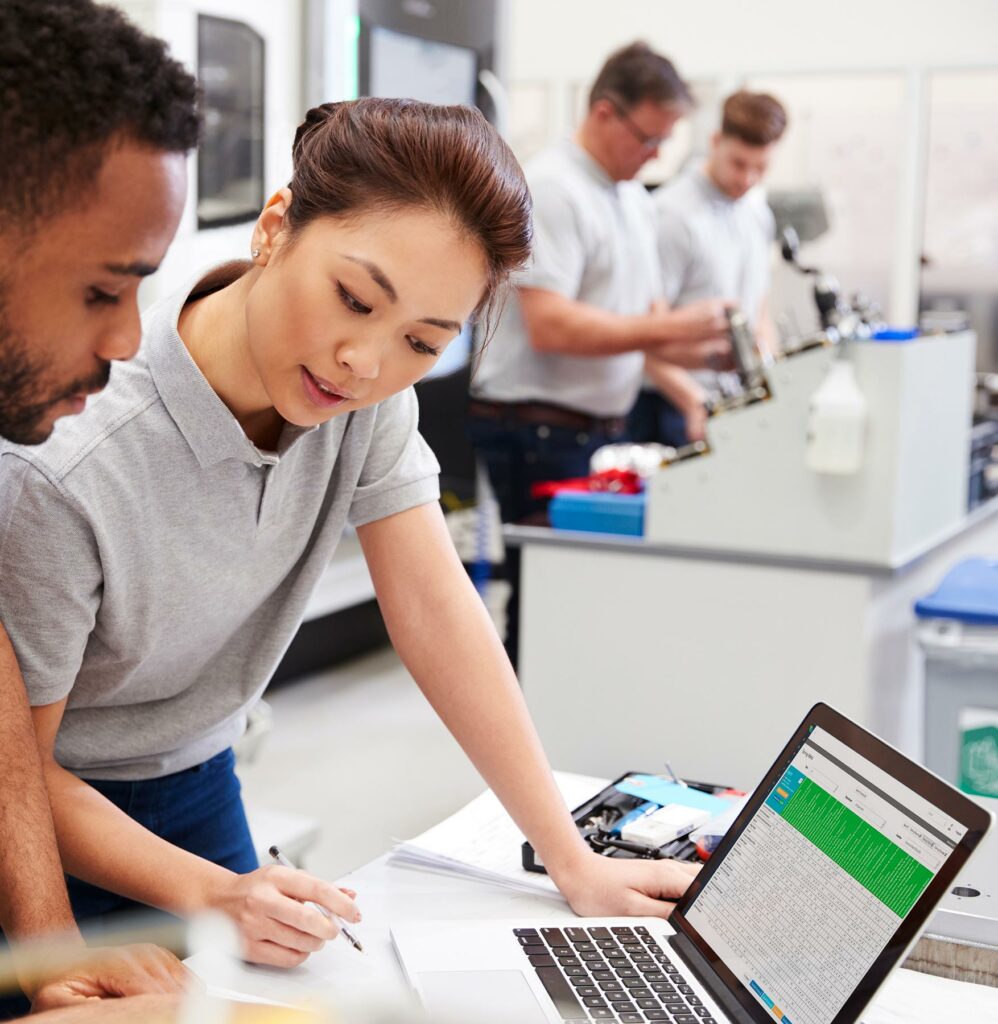 Two employees review a training matrix at work.