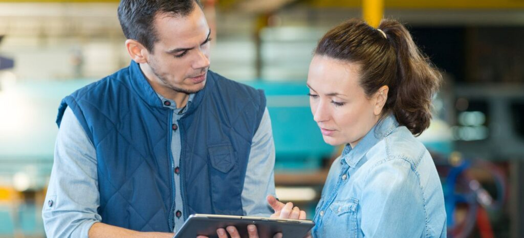 man and woman checking a tablet in factory