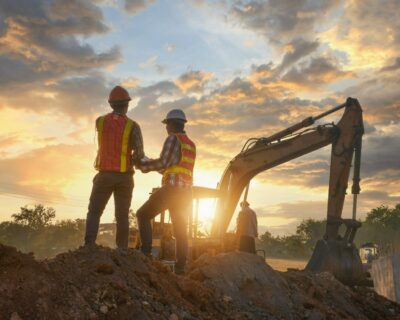 Construction engineers supervising progress of construction project stand on new factory,Engineering Consulting People on construction site holding blueprint in his hand. Building inspector.