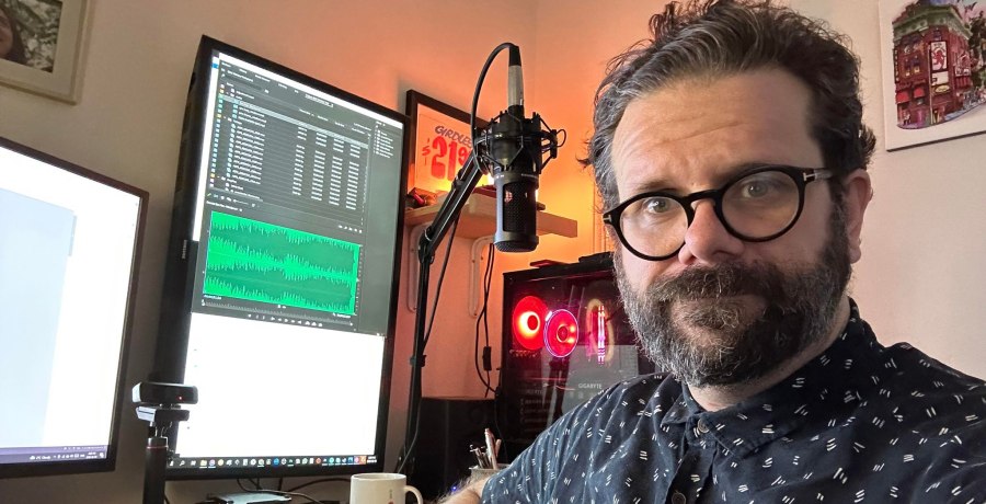 A bearded man wearing a blue collared tee shirt with a cream pattern. The team member is Nick Dolinski, he works for bastion and is in front of his computer edting safety courses.