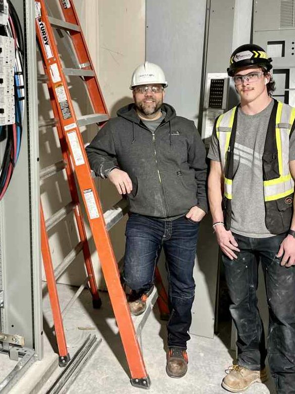 Bastion safety team out in the field, inspecting and consulting near a large electrical panel. 