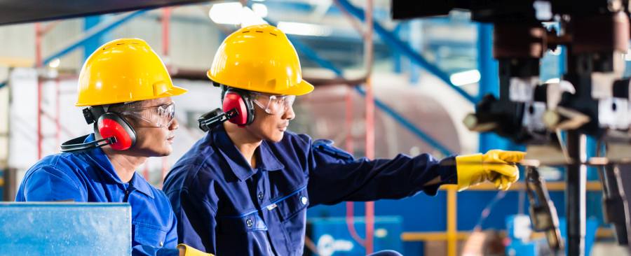 Workers in Asian factory at industrial metal cutting torch machine pointing out things that require preventive action.