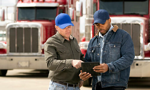 A royalty free image from the trucking industry of two truck drivers having a meeting using a tablet computer.