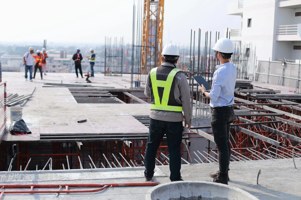 Construction workers using Behavior-Based Safety practices during a site inspection on a high-rise building project.