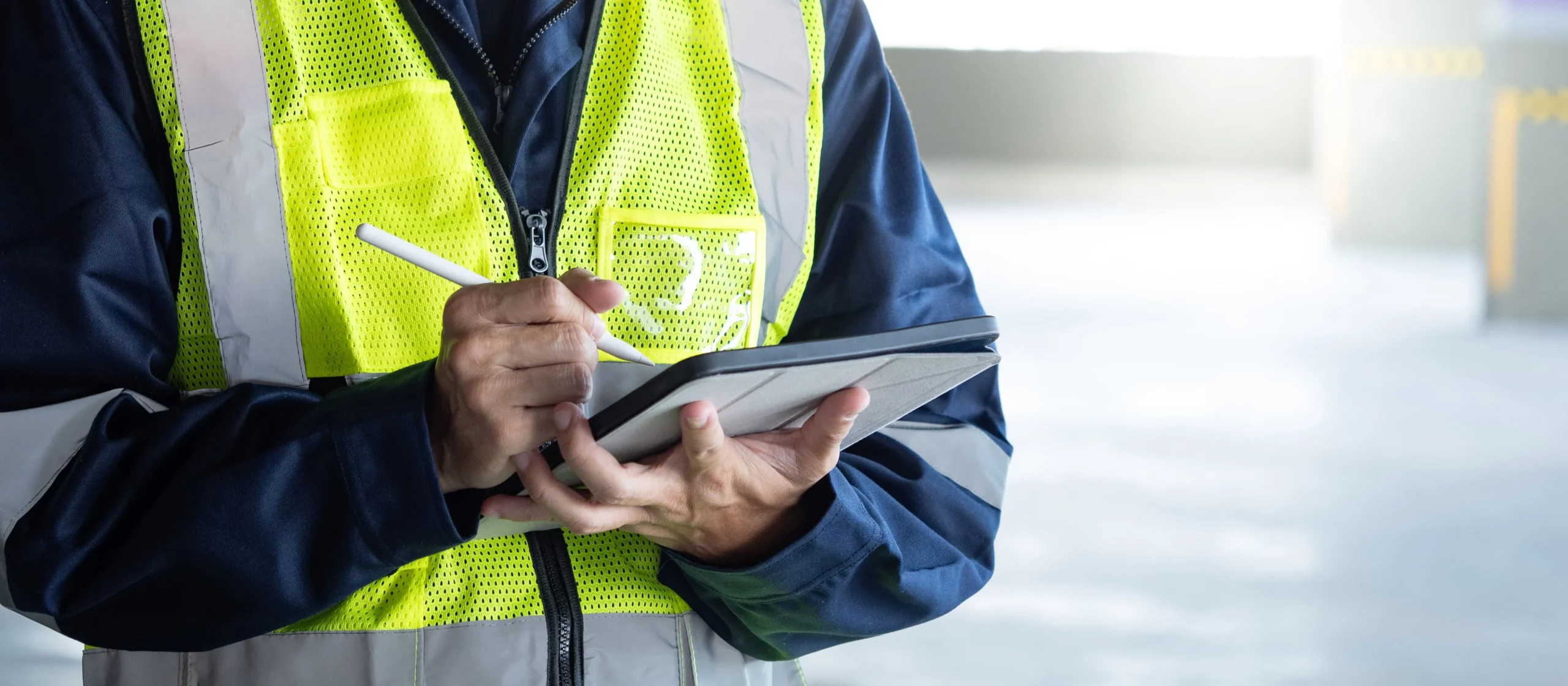 Safety inspector documenting nonconformance findings on a digital tablet during a workplace audit.