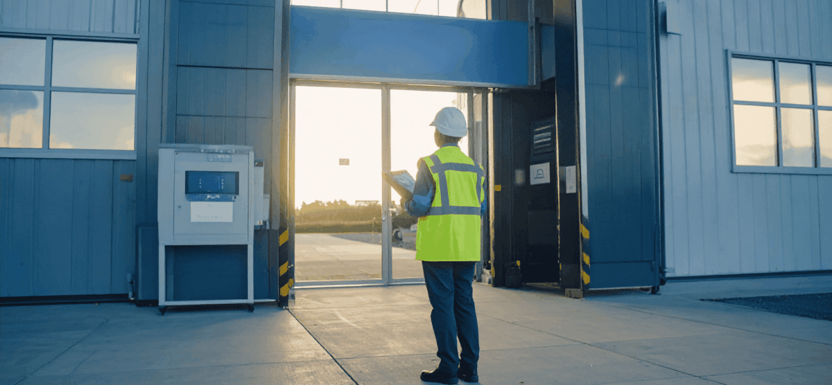 Worker standing outside industrial site at sunrise, reviewing safety procedures before first shift.
