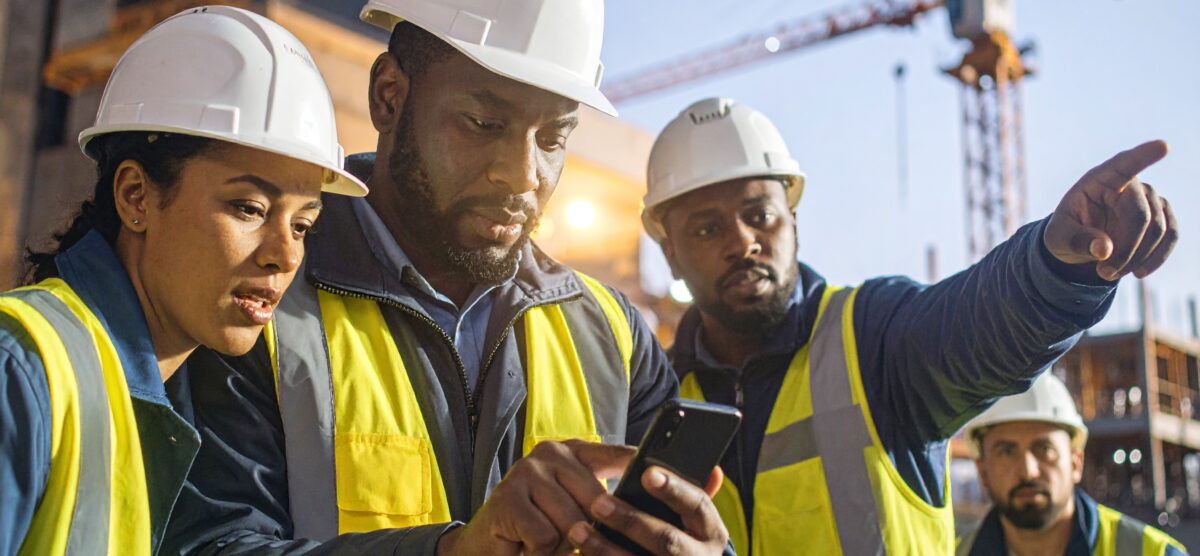 Field safety officers checking hazard identification software on-site.