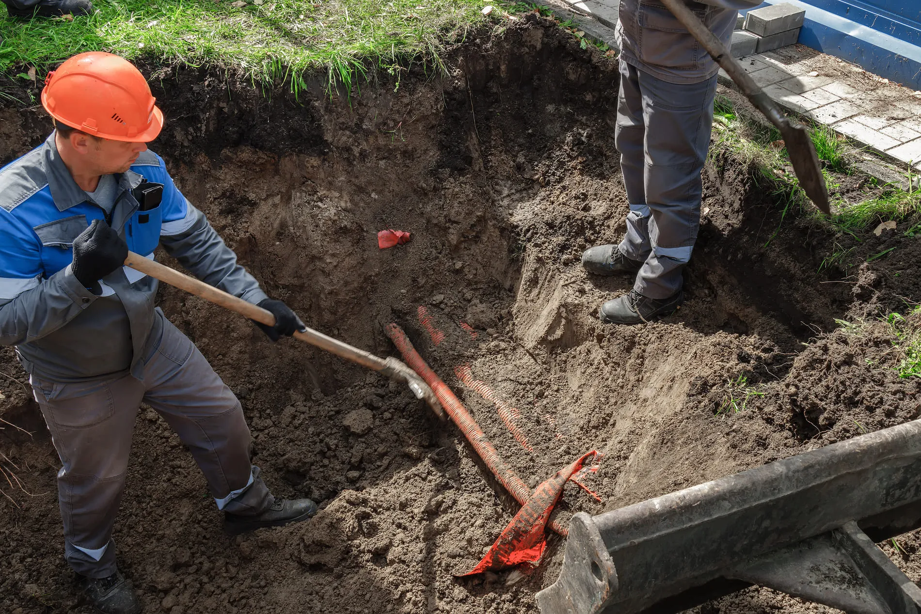 A technician securing a water line connection while following safe digging practices.