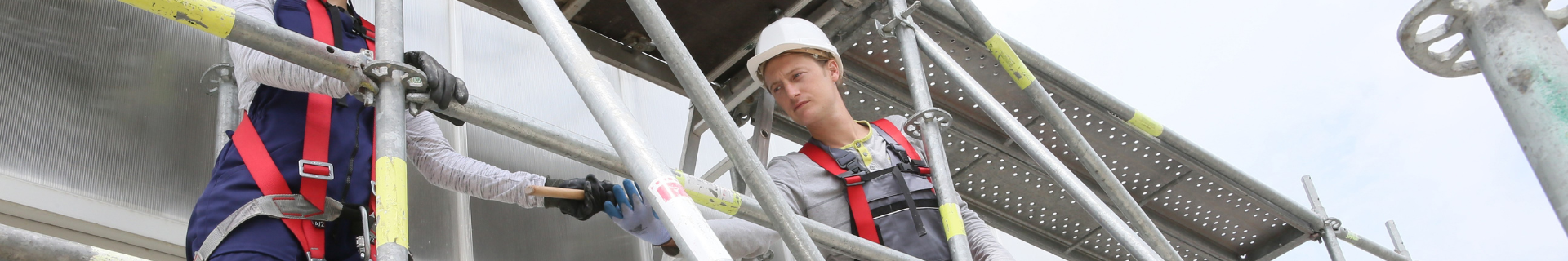 Construction worker with safety vest and hard hat on scaffolding at a U.S. job site.