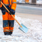 Facility crew shoveling snow on a sidewalk in freezing conditions as part of winter safety maintenance.
