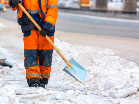 Facility crew shoveling snow on a sidewalk in freezing conditions as part of winter safety maintenance.