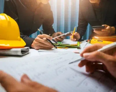 On-site safety team standing by a laptop reviewing an EHS vendor scoring matrix in front of a construction project.